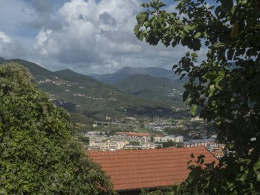 Punta Manara 'dan Riva Trigoso köyündeki hava manzarası, binalar, demiryolu, yollar ve bulutlu sonbahar gününde yeşil tepeler. Sestri Levante, Liguria, İtalya.