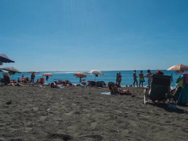 Riva Trigoso, Sestri Levante, Liguria, İtalya, 24 Eylül 2023: Güneşli sonbahar gününde Riva Trigoso köyünün kumsalında güneşlenen insanlar.