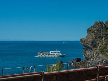 Manarola, Cinque Terre, Liguria, İtalya, 25 Eylül 2023: Deniz, kaya yolcu gemisi ve turist kalabalığıyla birlikte Anarola 'daki tren istasyonu platformundan görüntü.