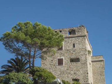 Eski taş kule, Torre Aurora, mavi gökyüzüne karşı ağaç. Monterosso al Mare, Liguria, İtalya. Cinque Terre Ulusal Parkı ve Unesco Dünya Mirası Alanı.