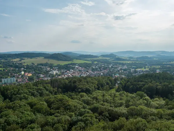 Kum taşı gözcüsü Jehla 'dan panoramik manzara Ceska Kamenice kasabası yakınlarında. Yeşil tepeli ve karışık ormanlı Lusatian Dağları 'nda yaz manzarası