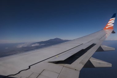 Tenerife, İspanya, 30 Ocak 2025: Akıllı Kanatlar havayolları ve Pico del Teide yanardağının kanatlı uçak penceresinden bakın. Tenerife, Kanarya Adaları üzerinde uçuş. Mavi gökyüzü arkaplanı, boşluğu kopyala.