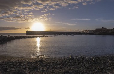 Playa de San Juan Körfezi 'nin altın gün batımı manzarası. Korunan kumsal ve küçük limanı var. Playa de San Juan, Tenerife adasının güneybatısında küçük bir balıkçı köyüdür..