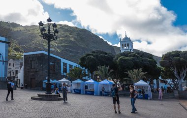 Garachico, Kanarya Adası, Tenerife, İspanya, 02 Şubat 2025: Central Square Plaza de la Libertad Santa Ana Kilisesi, market tezgahları, sokak lambası ve turist halkı.