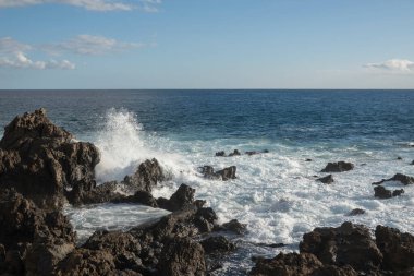 Tropik bir sahilde kara lav kayalarına çarpan dalgalar, Tenerife kanarya adasında su sıçraması.