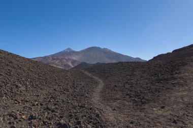 Renkli volkan Pico del Teide 'nin kış manzarası. Yürüyüş yolu Samara' dan kar lekeleri. Dağlar ve lav tarlaları mavi gökyüzüne karşı. El Teide Ulusal Parkı, Tenerife, Kanarya Adaları, İspanya.