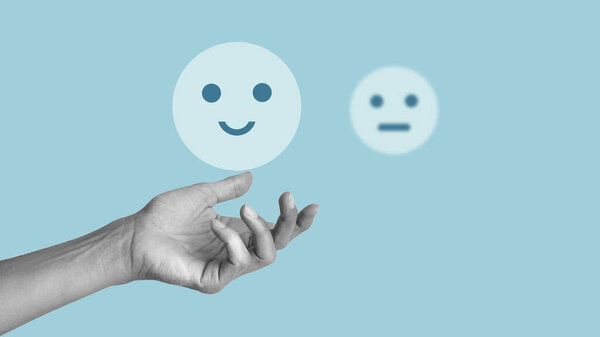 Выбор между негативным и позитивным в жизни человека. Грустное и радостное лицо в руке.