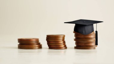 Madeni para stoklarında siyah mezuniyet şapkası, gelecekteki kariyeri için sıkı çalışan öğrenciler için güçlü bir çabayı resmediyor. Yurtdışında yüksek dereceli eğitim programı. Üniversite yardımları