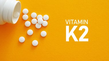 K2 vitamini tıbbi konsept olarak hapların metni ve fotoğrafı kullanılarak gösterilir
