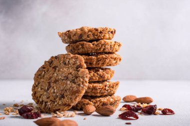 Granola enerji bisküvileri veya mısır gevrekli kurabiyeler, kurutulmuş kızılcık ve gri beton arka planda sağlıklı beslenme için fındık karışımı.