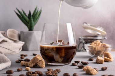 Homemade ice latte. Black coffee with ice and milk or cream in glass for tasty and refreshing break on grey kitchen background