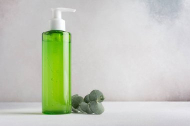 Transparent dispenser with green shampoo or shower gel and eucalyptus branch. Mockup for natural cosmetics and body care