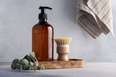 Çevre dostu mutfak konsepti, sürdürülebilir yaşam tarzı. Bulaşık fırçası, okaliptüs dolu okaliptüs şişesi, ahşap tepside temizlik için hazır.