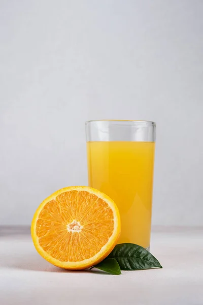 口感鲜橙汁在玻璃杯中 切碎橙子 叶子在灰色混凝土背景上 — 图库照片