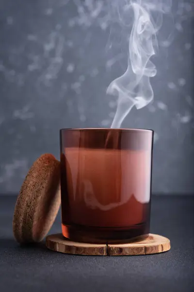 茶色のガラス瓶の中の居心地の良いキャンドル暗い背景に煙 — ストック写真