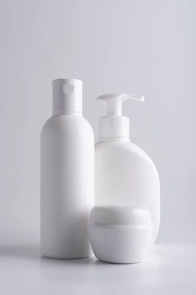 白い化粧品シャンプーボトル 化粧水ディスペンサーボトル クリームジャーモックアップグレーの背景 — ストック写真