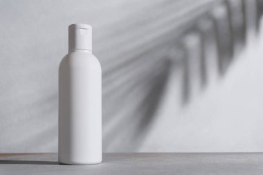 Doğal organik kozmetik beyaz şişe gölge palmiye yapraklarıyla taklit edilir. Spa ve sağlık konsepti.
