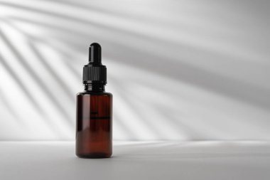 Model olarak palmiye yaprağı gölgesi olan kahverengi bir kozmetik şişesi. Doğal organik kozmetik ürünleri..