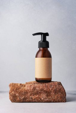 Kahverengi cam şişe kozmetik ürünler için taşın üzerinde duruyor. Doğal organik kozmetik konsepti