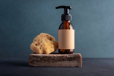 Kahverengi cam şişe ve deniz doğal süngeri gibi koyu bir arka planda. Banyo, kaplıca tedavisi konsepti.