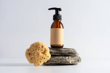 Gri bir arka planda taş bir podyumda kahverengi cam şişe ve deniz doğal süngeri gibi. Banyo, kaplıca tedavisi konsepti.