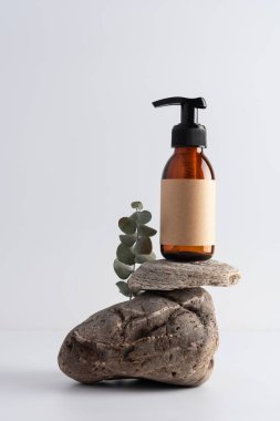 Beyaz gri bir arka planda taş bir podyumda cam pompa şişesini taklit et. Kozmetoloji, kaplıca tedavisi konsepti.