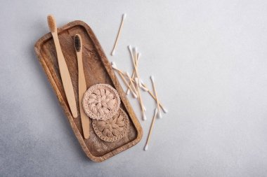 Çevre dostu ve kişisel bakım için sıfır atık tuvalet malzemesi. Bambu diş fırçaları, pamuk tomurcukları ve ahşap tepside tığ işi pamuk yüz yastıkları.