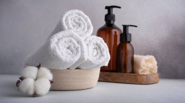 Pamuk çiçekli beyaz havlular ve kaplıca ve banyo için gri arka planda şeker şişeleri..