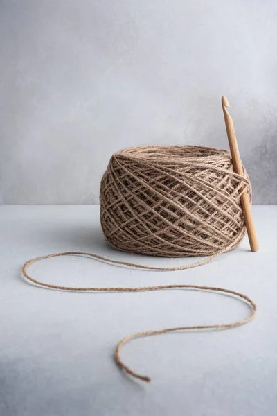 Skein of jute rope with wooden crochet hook for craft and handmade on a gray background