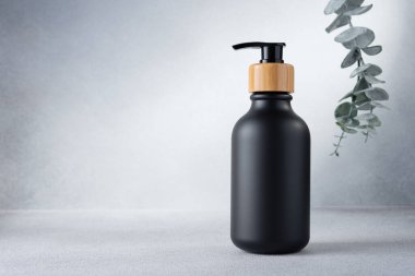 Doğal kozmetik ürünleri için siyah şişe ve okaliptüs. Boş ürün paketleme şablon tasarımı.