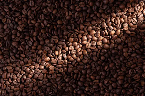 Texture of roasted coffee beans with contrasting dramatic light effect.