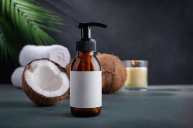 Kahverengi cam şeker şişesi ve koyu arka planda taze hindistan cevizi ve palmiye yaprakları. Hindistan cevizi yağlı organik doğal kozmetik ürünler. Markalaşma için plastik ambalaj ürünleri, modelleyin.