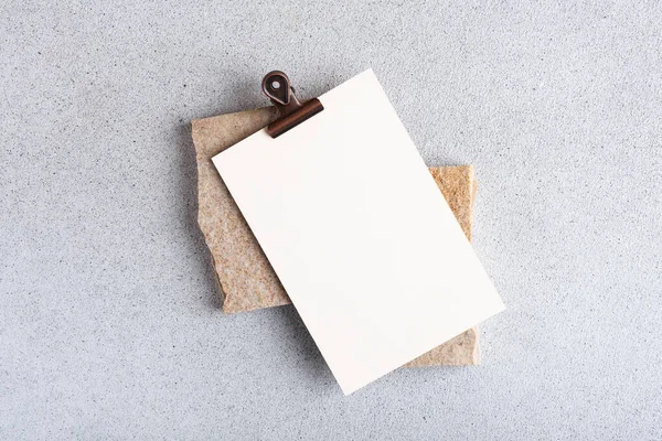 Blank paper sheet card with binder on stone background. Mockup scene for design.