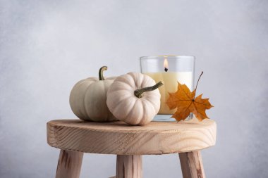 Küçük dekoratif balkabakları ve aroma mumu ahşap taburede rahat bir sonbahar evi dekoru olarak.
