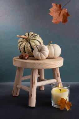 Küçük dekoratif balkabakları ve aroma mumu ahşap taburede rahat bir sonbahar evi dekoru olarak.