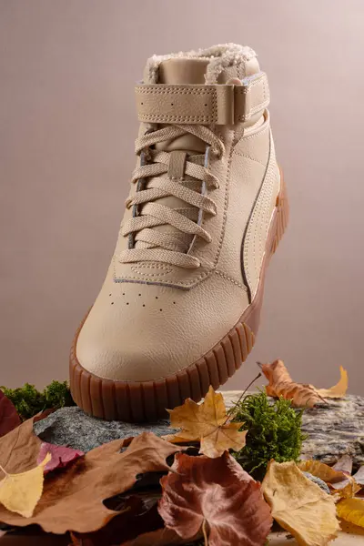 Beige leather casual boots on brown autamn background. Creative photography for an advertising poster for footwear commercials