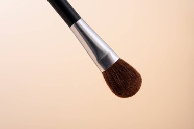 Pastel bej arka planda izole edilmiş yüz pudrası uygulamak için makyaj fırçası