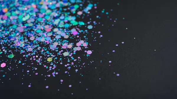 Multicolored glitter on black background. Festive texture background with selective focus.
