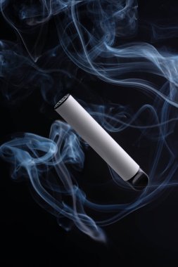 Beyaz elektronik sigara ya da siyah arka planda dumanlı bir tüp. Modern sigara, buhar ve nikotin konsepti.