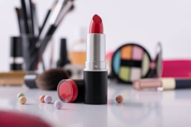 Dekoratif makyaj sehpası ve ön planda kırmızı ruj, seçici odaklanma. Güzellik ürünü ve makyaj konsepti. 