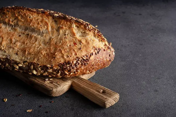 Ev yapımı organik tahtadan yapılmış tahıl ekmeği. Sağlıklı beslenmek için tahıl unundan yapılmış lezzetli kahverengi ekmek.