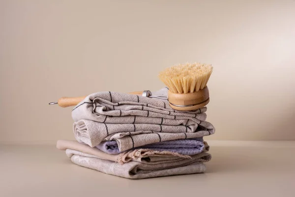 Eco wooden dish brush and stack of linen and cotton napkins. Kitchen cleaning concept for eco-friendly and sustainable lifestyle.