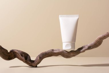 Beyaz kozmetik tüpü ahşap bir dal podyumda, maket için. Sağlıklı kozmetoloji, cilt bakımı ve güzellik tedavisi yaratıcı kavram. 