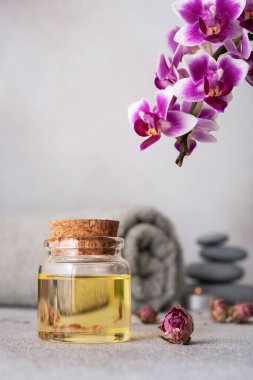 Gerekli yağları, pürüzsüz çakıl taşlarını, sarılmış gri bir havluyu ve canlı mor bir orkideyi barındıran sakin bir spa. Kompozisyon sakinlik ve denge yayar, rahatlık ve rahatlama temaları için mükemmeldir..