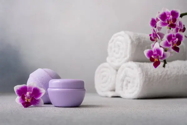 Lilac Βάζο Καλλυντική Κρέμα Μπάλα Μπάνιου Και Τυλιγμένες Πετσέτες Γκρι Εικόνα Αρχείου