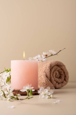Yanan mum spa odasındaki masaya aroma yayıyor. Pastel renkli mum ve kiraz çiçekli dal ile kaplıca tedavisi için güzel bir kompozisyon.. 