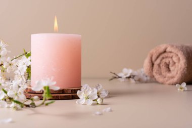 Yanan mum spa odasındaki masaya aroma yayıyor. Pastel renkli mum ve kiraz çiçekli dal ile kaplıca tedavisi için güzel bir kompozisyon.. 