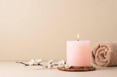 Yanan mum spa odasındaki masaya aroma yayıyor. Pastel renkli mum ve kiraz çiçekli dal ile kaplıca tedavisi için güzel bir kompozisyon.. 