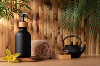 Siyah bir losyon şişesi ya da duş jeli, bambu duvarına karşı ahşap bir tepside oturur. Vücut bakımı ürünü, tropikal kaplıcada modelleme yapıyor. Sağlık ve bencillik kavramı.