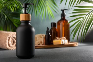 Vücut bakım ürünleri için siyah bir losyon şişesi ya da duş jeli. Tropikal spa iç mekanında model alınır. Sağlık ve bencillik kavramı.